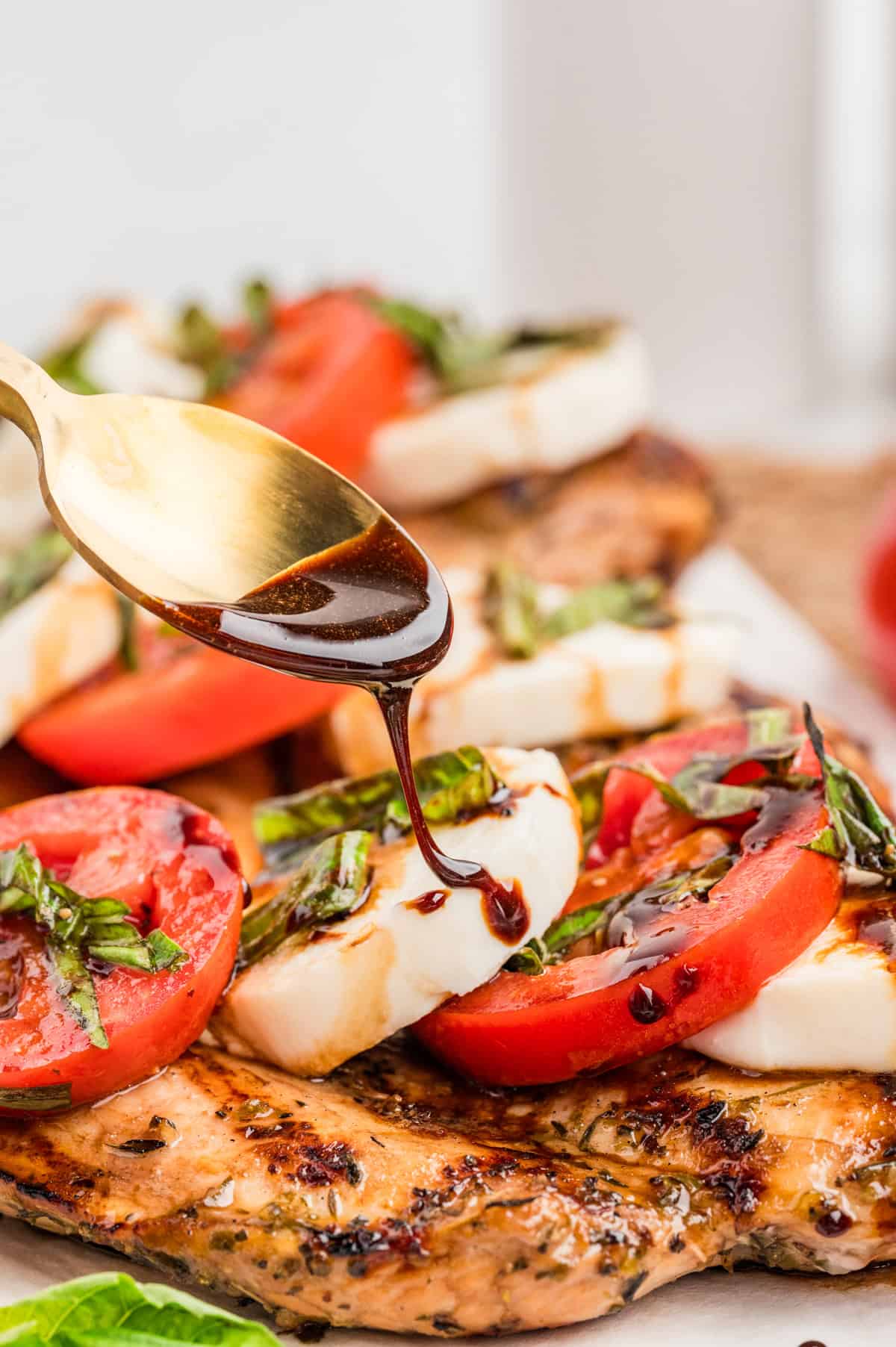 Drizzling balsamic glaze over chicken caprese