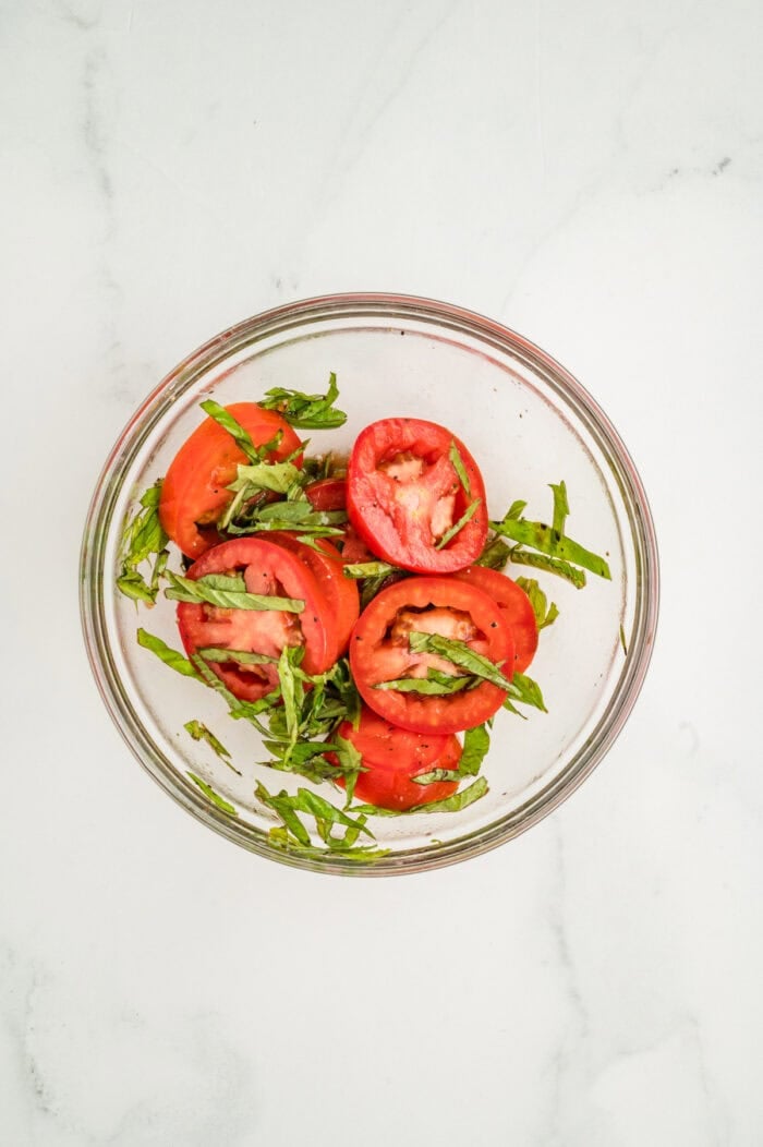 Sliced tomatoes and basil in a bowl