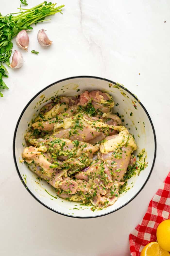 Chicken thighs marinating in chimichurri sauce