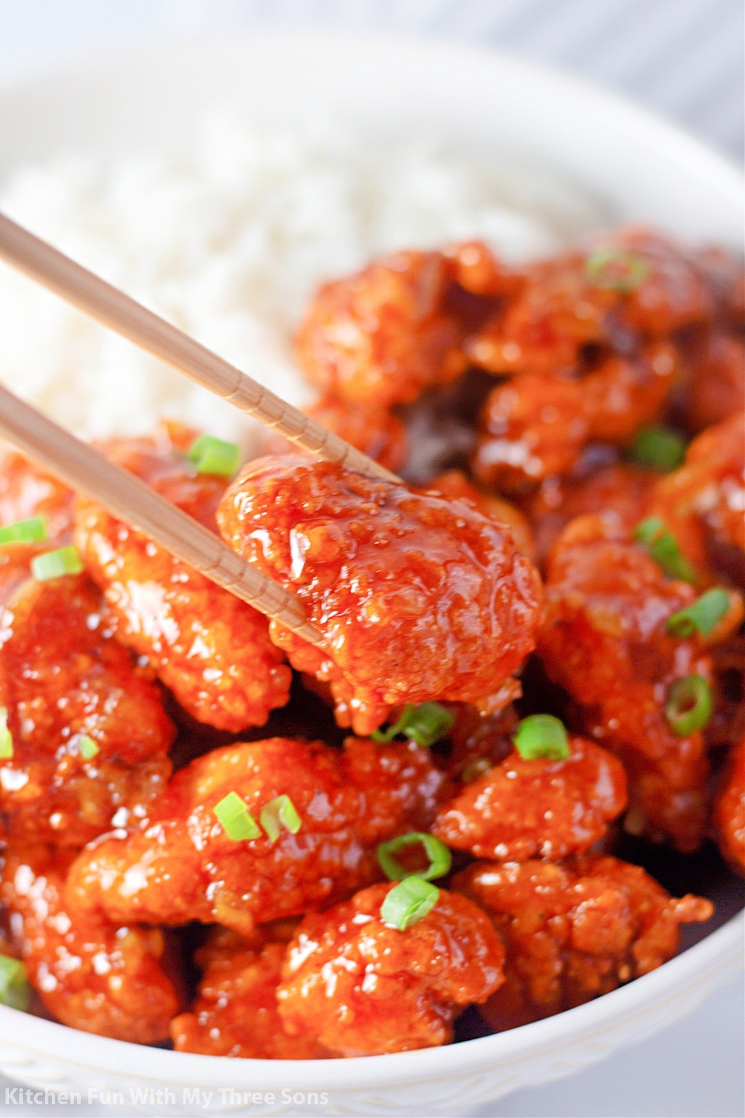 lifting a piece of chicken with chopsticks.