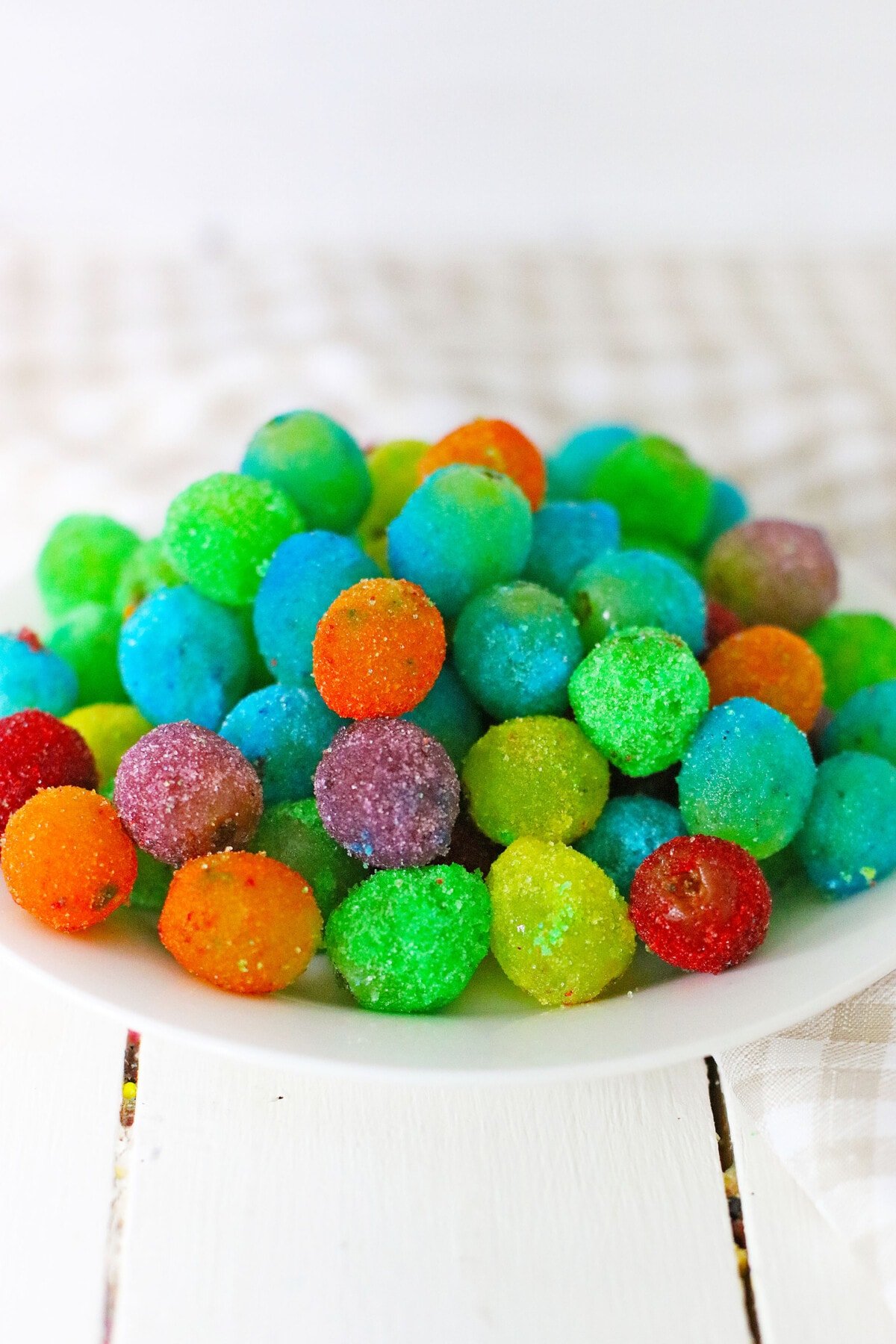 Candy Grapes are frozen grapes dipped and coated in a thin layer of vibrant and flavored Jello mix. Frozen Jello Grapes on a plate