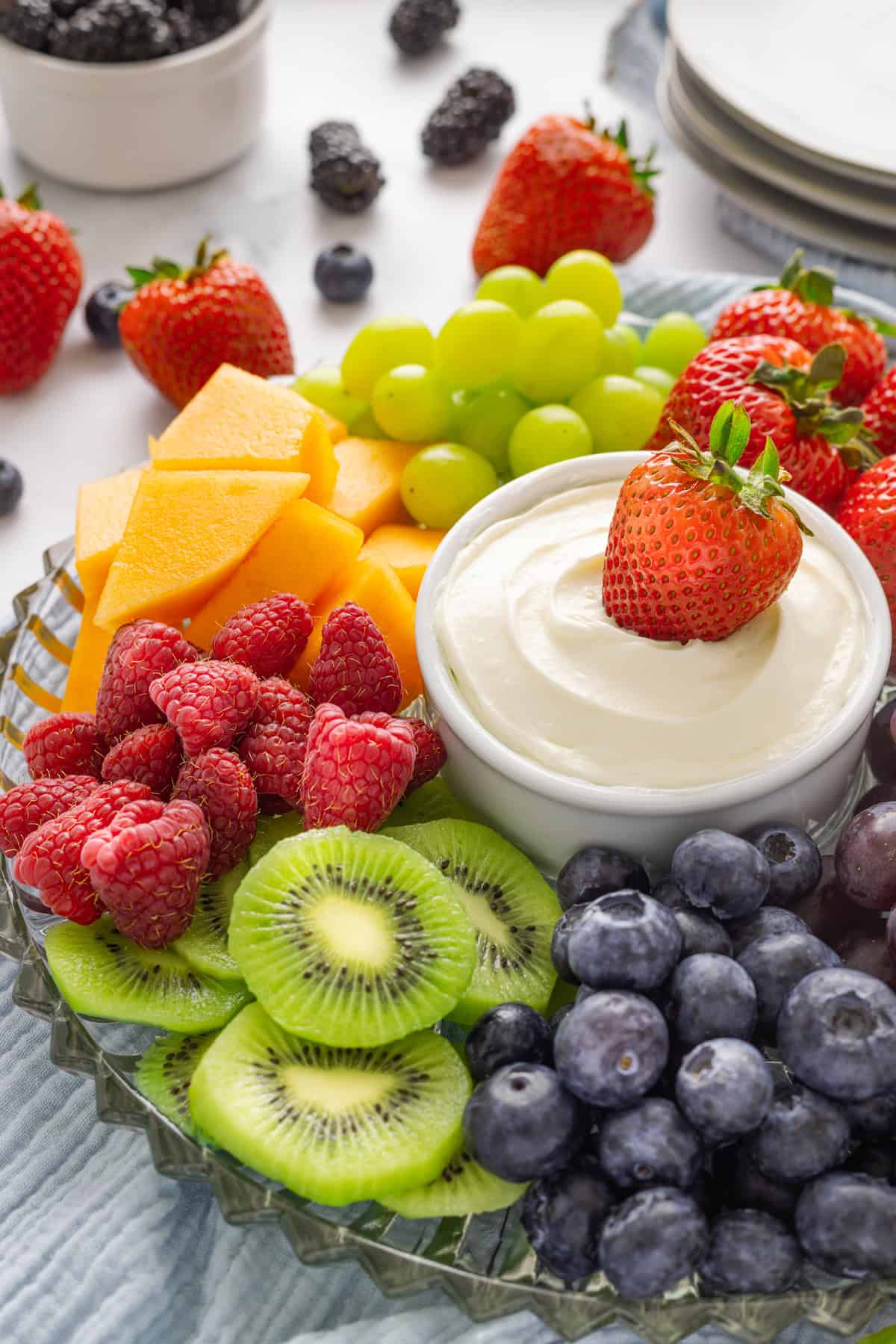 A bowl of fruit dip with a strawberry surrounded by other fruit