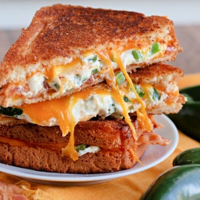 Halved jalapeno popper grilled cheeses stacked on a plate.