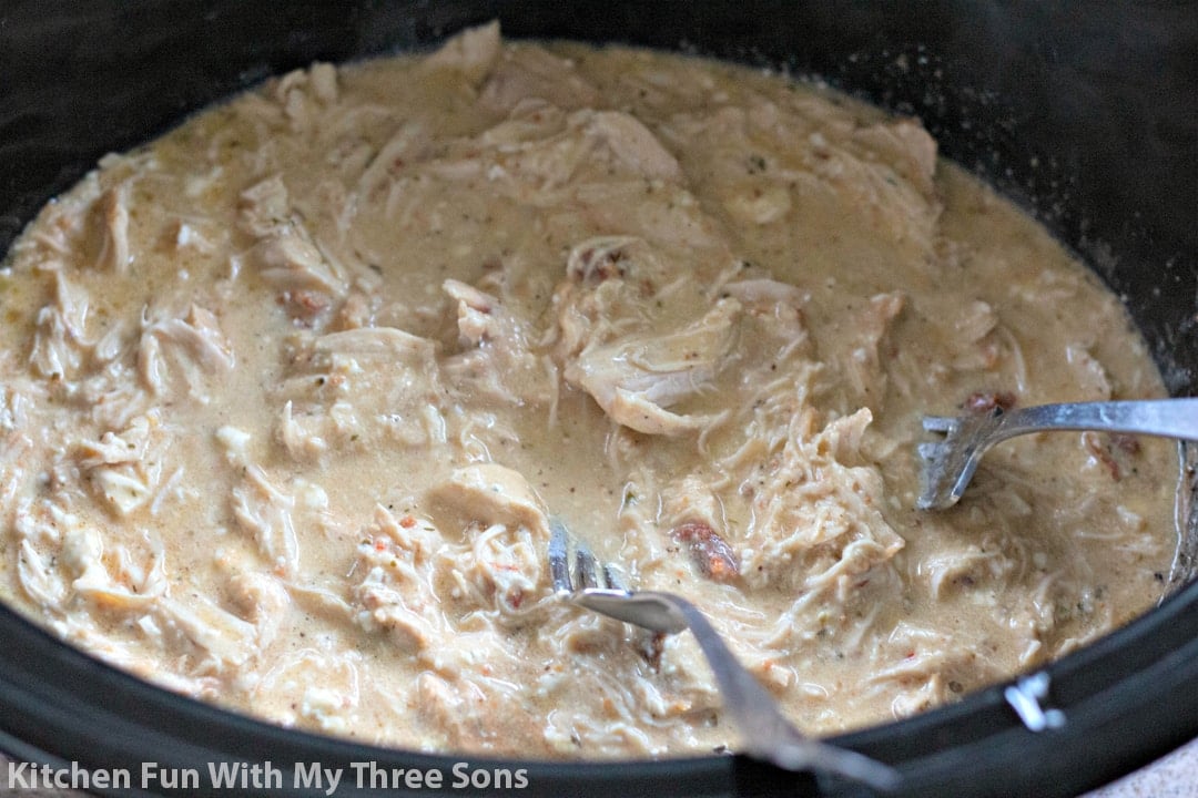 shredding chicken in the Crock Pot with forks