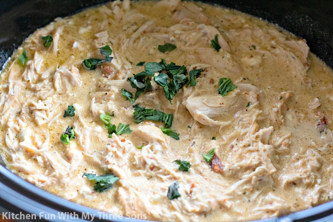 adding torn basil leaves to the shredded chicken