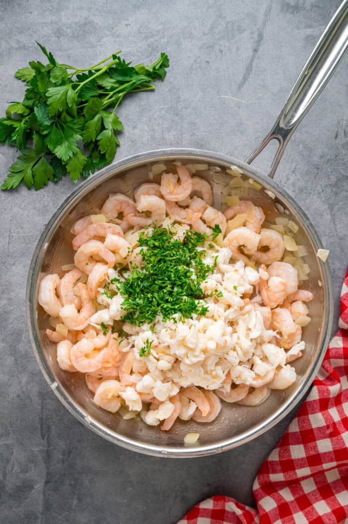 Crab meat and parsley added to a pan with shrimp